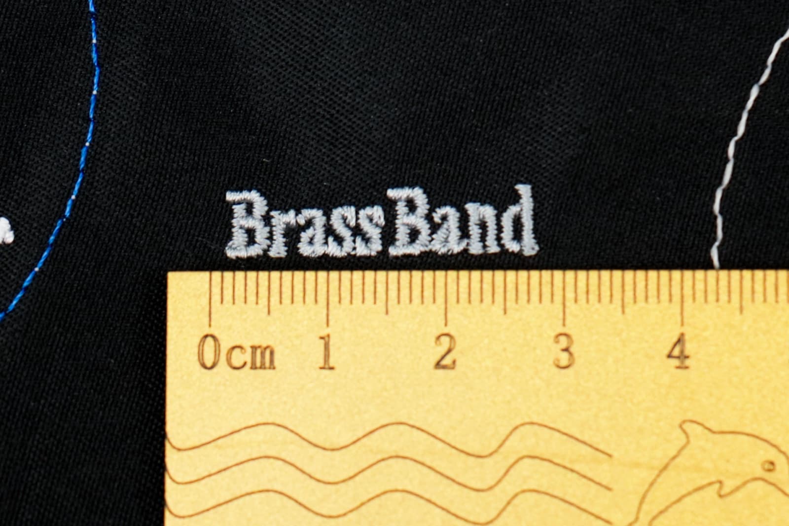 Macro of small embroidered text on a polo shirt chest, legible at 5mm height