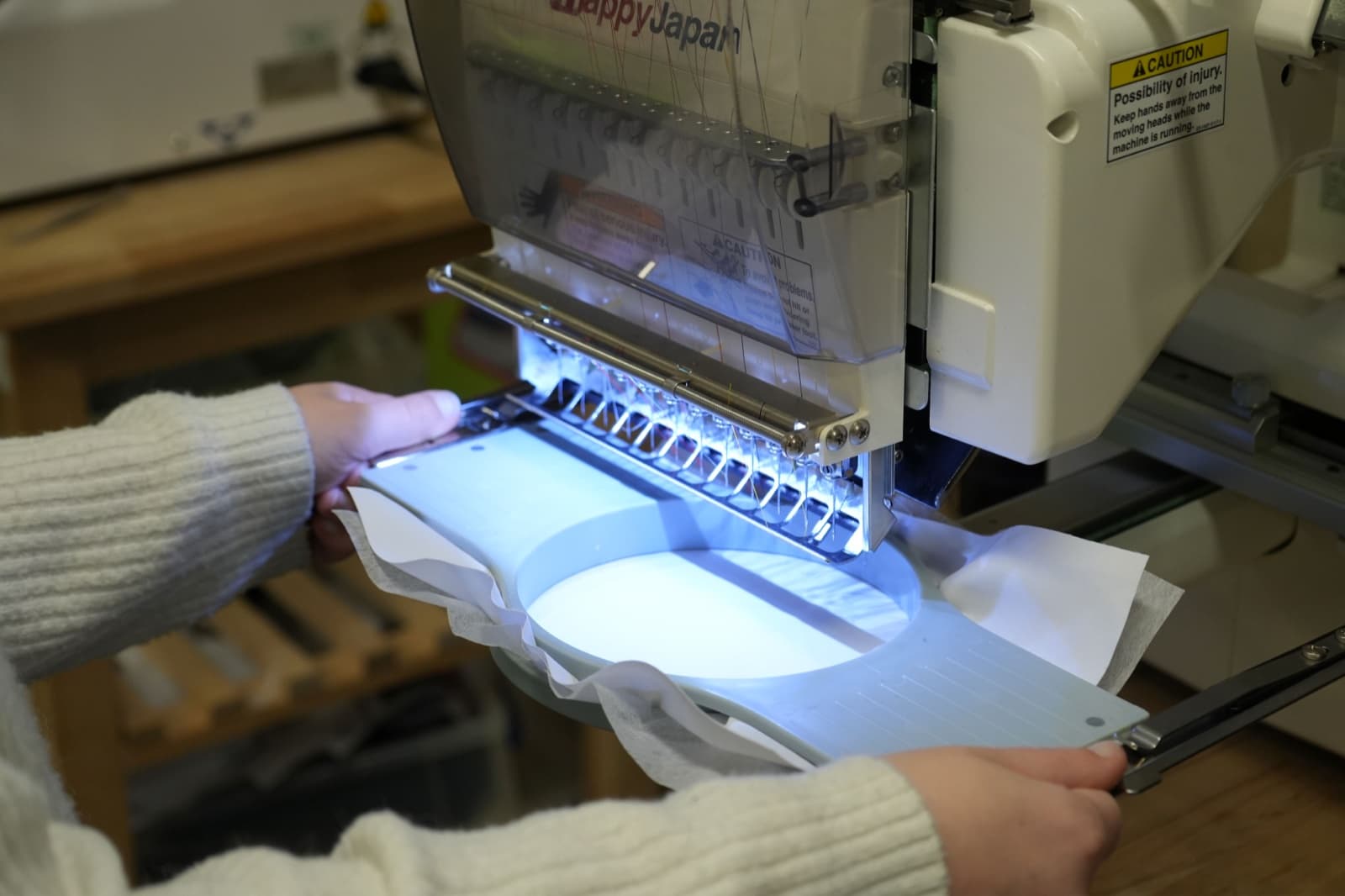 Hands loading a fabric hoop into a commercial embroidery machine