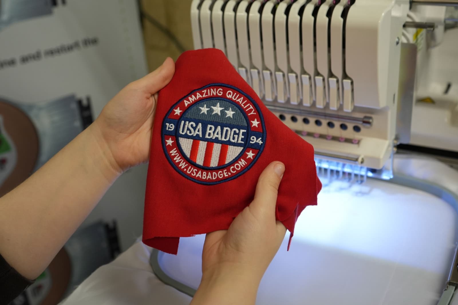 Hands holding a finished embroidered piece for quality inspection