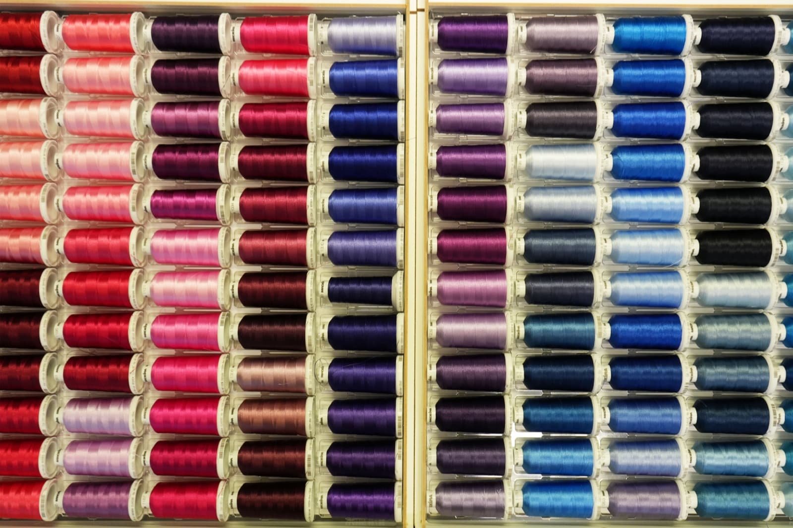 Wall of embroidery thread cones in many colors arranged by hue